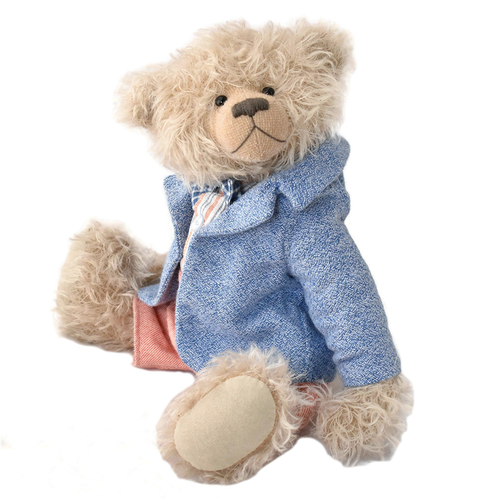 Teddy bear wearing a blue coat on a white background